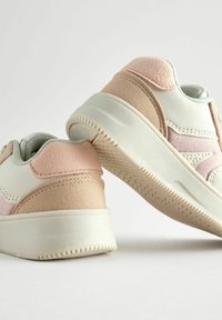 Hvide og pink sneakers med ruskindsdetaljer, rund tå og tekstureret gummisål med et låg profil design.