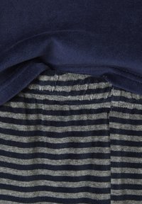 Close-up of navy blue fabric over gray and navy blue striped soft fabric with gathered elastic detail.
