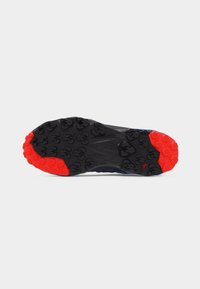 Σόλα παπουτσιού με μαύρη και κόκκινη ελαστική σόλα σχεδιασμένη για πρόσφυση, με γωνιακά και εξαγωνικά μοτίβα στις περιοχές της φτέρνας και των δαχτύλων.