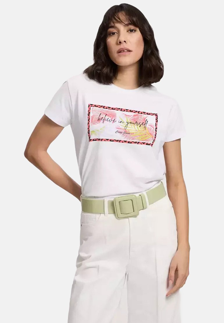 Biała koszulka z kolorową grafiką "uwierz w siebie" otoczoną czerwono-czarnym wzorem ze wzorem lamparta. Modelka nosi jasnoniebieski pasek z kwadratową klamrą.