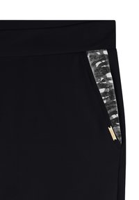 Pantalones de chándal negros con un bolsillo lateral que presenta un patrón de camuflaje gris y una pequeña etiqueta dorada de acento. Textura de tela suave.