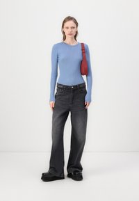 Long-sleeve light blue ribbed top, paired with loose, dark gray jeans. A red shoulder bag added; chunky black platform shoes complete the look.