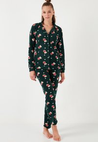 Conjunto de pijama de franela verde con un patrón floral, que incluye una camisa de botones de manga larga y pantalones ajustados, con textura acanalada y lunares.