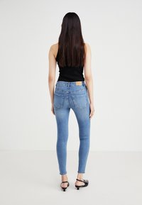 Tievās zilo džinsu bikses ar vidēju jostas augstumu, piecām kabatām un gaišu mazgāšanu. Iezīmētas ar zīmola ādas uzlīmi aizmugurējā jostā.