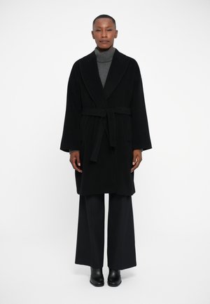 Black robe made of soft fabric with a belt, featuring a shawl collar and wide sleeves. Paired with a gray turtleneck and black wide-leg pants.
