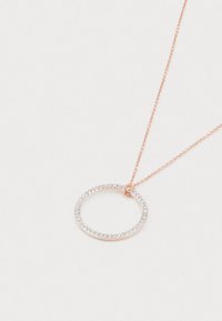 Rose-guld kædedyse med en cirkulær vedhæng udsmykket med små glitrende klare ædelstene på en hvid baggrund.