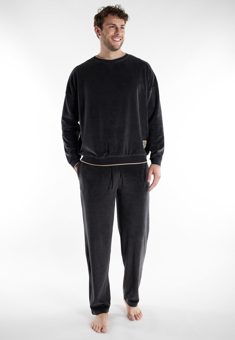Zwart pyjama-set gemaakt van zachte stof; lange mouwen top met een ronde hals en bijpassende drawstring broek met een subtiele beige accent bij de taille.