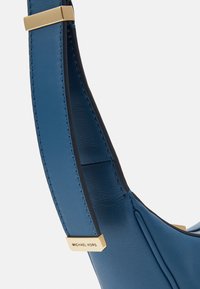 Sangle de sac à main en cuir bleu profond avec des accents noirs. Équipée de matériel en or et de coutures contrastées pour la durabilité et le style.