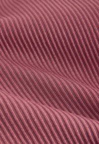 Mintás szövet diszkrét mályva színben, függőleges bordázott mintákkal, amely puha és sima tapintású. Ideális ruházathoz vagy kárpitokhoz.