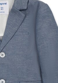 Blazer in denim per bambini, caratterizzato da un colore azzurro chiaro, tessuto testurizzato, rever a scollo a V, taschino sul petto e due bottoni frontali.