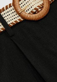 Tessuto nero con una cintura intrecciata in paglia, dotata di una fibbia rotonda in similpelle marrone, arricchita da un motivo beige lungo il bordo.