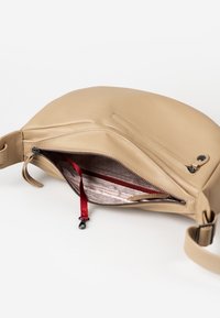 Beige leather bag with a curved design, featuring a zipper closure and a red fabric interior pocket with a pull tab.