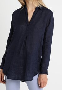 Navyblauwe linnen shirt met een kraag, lange mouwen en een losse, relaxte pasvorm. Heeft een knoopsluiting en een subtiele textuur.