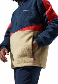 Fleece pullover in marineblauw, rood en beige. Voorzien van een hoge kraag, halve ritssluiting en zijzakken. Getextureerde stof met contrasterende kleurpanelen.