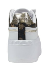 Sneaker bianco con un accento metallico dorato sul tallone e dettagli neri a motivo. Suola in gomma spessa con borchie sul tallone.