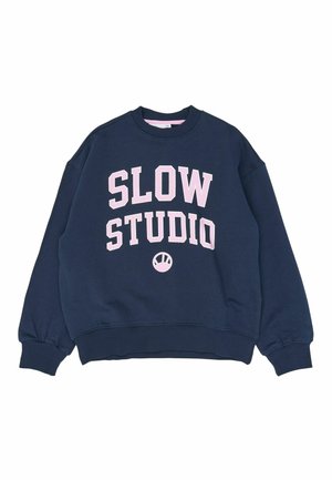 Granatowa bluza z okrągłym dekoltem z różowym napisem „SLOW STUDIO” oraz małym, okrągłym logo umieszczonym poniżej napisu na środku.