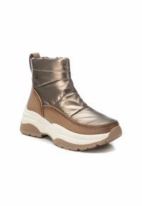Botas de tobillo acolchadas marrones con un acabado brillante, que cuentan con una sección inferior texturizada en beige, suela blanca gruesa y una lengüeta en la parte trasera.