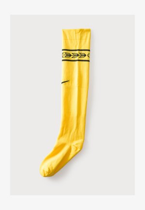 Calza sportiva giallo brillante con motivo a freccia nera vicino alla parte superiore e logo nero swoosh nella zona superiore del piede.