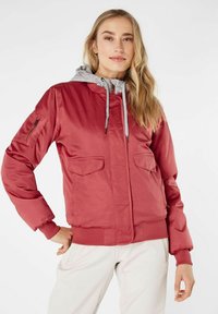 Chaqueta bomber roja con capucha gris, que cuenta con bolsillos con cremallera y solapa, puños acanalados y una textura suave y brillante.