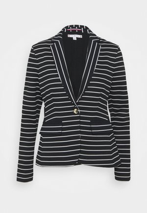 Blazer negro con rayas horizontales blancas, cierre con un solo botón dorado, solapa con muesca y bolsillos frontales con solapas.