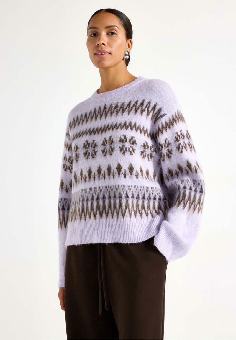 Maglione lavorato a maglia di un leggero colore viola con motivi geometrici marroni, caratterizzato da maniche lunghe e una vestibilità ampia. Finitura morbida e testurizzata.