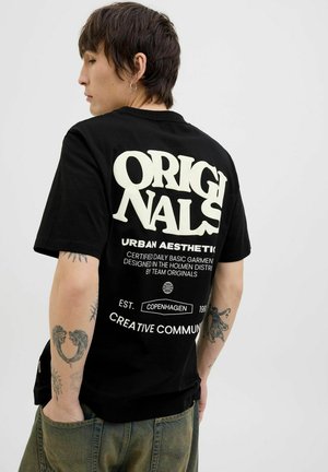 Camiseta de algodón negra con gran texto blanco en la parte posterior: "ORIGINALS" y "URBAN AESTHETIC", con detalles gráficos adicionales y un ajuste holgado.