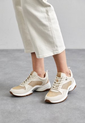 Baskets de sport beiges avec une tige texturée, des accents en daim, un design à lacets et des semelles en caoutchouc. Comprend une sangle à l'arrière et des détails scintillants légers.