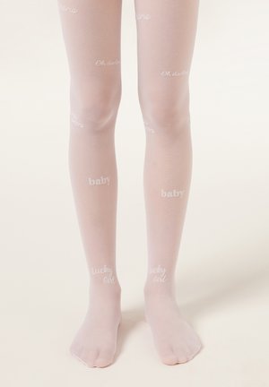 Ben iført tynde lyserøde strømpebukser med hvide tekstmønstre, der siger "baby," "heldig pige" og "åh skat," på en ensfarvet baggrund.