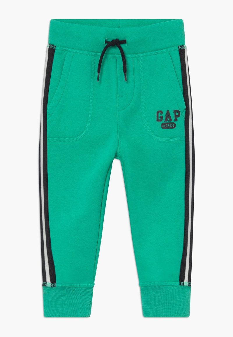Pantalon de jogging vert pour tout-petit avec bandes latérales noires et blanches, cordon noir, poches avant et logo GAP sur la poche droite.