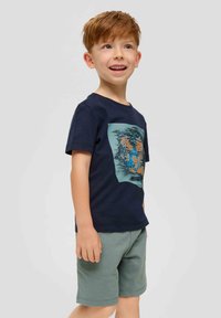Marineblaue Baumwoll-T-Shirt mit einem Tiger-Graphic in Orange und Blau, kombiniert mit grünen Shorts. Kurzärmlig und klassischer Schnitt.