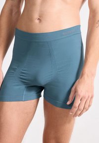 Herrarnas boxershorts i teal. Slät tyg med en figurnära design, elastisk midja och förstärkt ficka för stöd. Enkla sömnadsdetaljer.