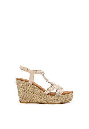 Sandalia de cuña beige con tiras trenzadas, hebilla en el tobillo y plataforma con suela de cuerda tejida.
