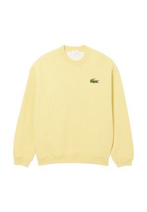 Sudadera amarilla de tejido suave, con cuello redondo, mangas largas y un pequeño logo de cocodrilo verde en el lado izquierdo del pecho.