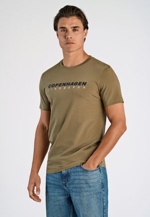 Camiseta de manga corta verde oliva con el atrevido texto "COPENHAGUE LINDBERGH", cuello redondo y tejido suave sobre un fondo claro.