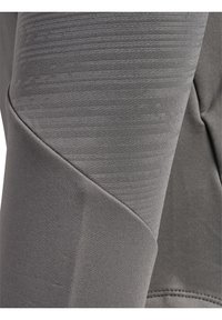 Primer plano de tela gris con costuras visibles y sutiles variaciones de textura en la manga de una prenda o en la pierna de un pantalón.