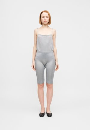 Graues geripptes Tanktop und passende mittellange Shorts aus weichem Stoff, mit dünnen Trägern und einem elastischen Bund. Schwarze flache Schuhe.