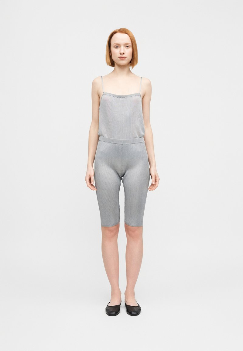 Γκρι ριμπ αμάνικο τοπ και ταιριαστά σορτς μεσαίου μήκους, κατασκευασμένα από μαλακό ύφασμα, με λεπτές τιράντες και ελαστική μέση. Μαύρα πάνινα παπούτσια.