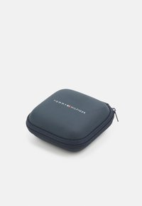 Blaues Reißverschlussetui mit glatter Textur und quadratischer Form. Verfügt über das weiße "TOMMY HILFIGER"-Logo auf der Oberseite. Kompaktes und langlebiges Design.