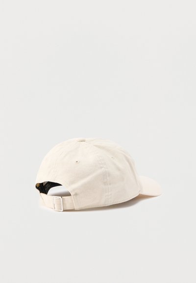 Casquette de baseball en coton blanc cassé avec sangle réglable et boucle métallique, vue de dos sur un fond clair uni.