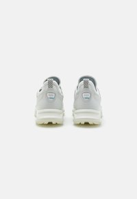 Grå sneakers med en glatt læroverdel, teksturert hæl og hvit gummisåle. Har en trekkstropp og blå detaljer på hælen.