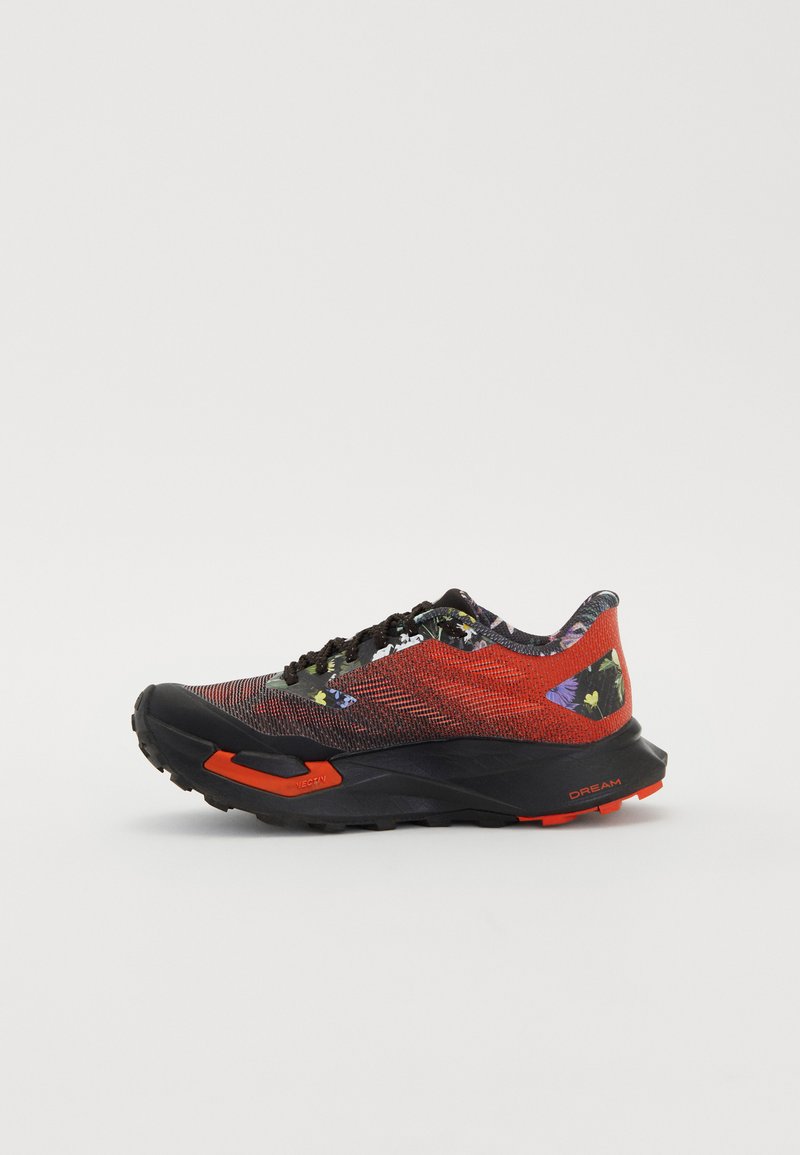 Chaussure de course avec un dessus en mesh rouge respirant, une semelle en caoutchouc noire et des accents floraux, équipée de lacets noirs et d'accents orange sur la semelle intermédiaire.