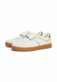 Sneaker bianche con accenti dorati e texture in suede e pelle. Presentano una suola in gomma e una striscia in Velcro per la chiusura.