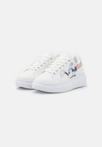 Zapatillas blancas con un diseño de corte bajo, material sintético suave y acentos en rosa. Presenta un gráfico de un personaje de dibujos animados en el lateral. Suela de goma.