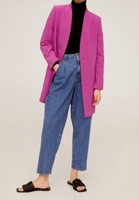 Fuksia pitkä bleiseri, musta istuva turtleneck, korkeavyötäröiset siniset farkut ja mustat liukuvaikutteiset sandaalit. Silkkinen kangas, muotoiltu istuvuus.