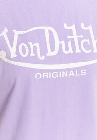Fialové bavlněné tričko s bílým grafickým textem "Von Dutch" s opotřebenými akcenty a slovem "ORIGINALS" níže.