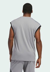 Top atlético sin mangas de color gris con un escote redondeado. Presenta detalles en negro a lo largo de las costuras de los hombros y una textura de tela suave y transpirable.