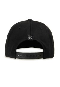 Black snapback cap with a flat brim, featuring a circular DC logo tag at the back and a textured fabric finish. Adjustable strap included.