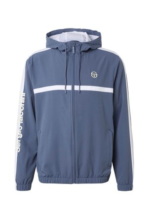 Veste à capuche bleue zippée avec une bande blanche horizontale sur la poitrine, des rayures blanches sur les manches et le texte "Sergio Tacchini" sur le bras gauche.