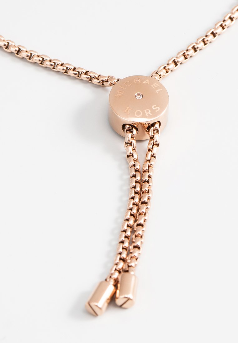 Collana a catena color oro con un fermaglio centrale rotondo incavato e due fili regolabili intrecciati. Finitura lucida e maglie uniformi.