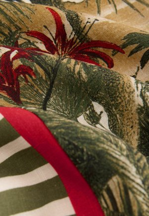 Tissu avec un motif tropical comportant des fleurs rouges et des feuilles vertes sur un fond beige, accentué par des bords rayés rouges et verts.